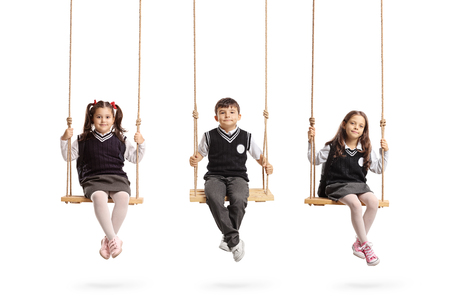 Schoolchildren sitting on wooden swings isolated on white backgroundの写真素材