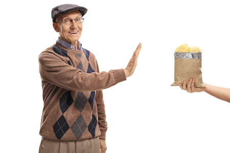 Elderly man refusing a bag of chips isolated on white backgroundの写真素材