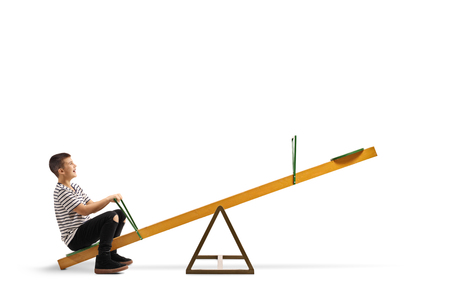 Full length shot of a smiling boy sitting alone on a seesaw isolated on whiteの写真素材