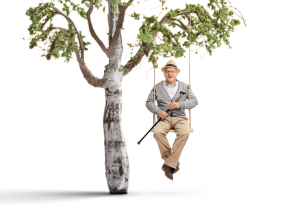 Elderly man on a swing hanging from a tree branchの写真素材