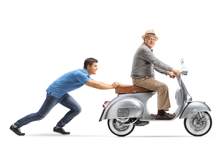 Full length shot of a young guy pushing an elderly man on a vintage scooter isolated on white backgroundの写真素材