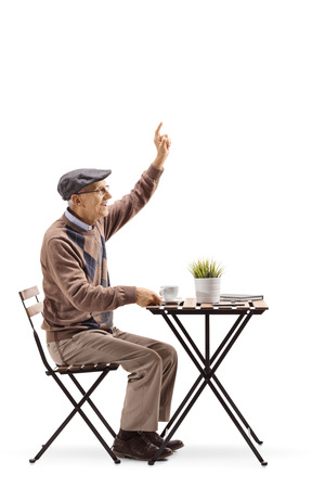 Full length profile of a senior man sitting at a coffee table and gesturing to call a waiter isolated on whiteの写真素材