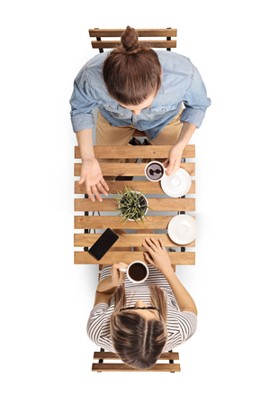 Top view of a young man sitting at a wooden table with a cup of coffee and talking to a young woman isolated on white backgroundの写真素材