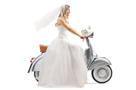 Full length profile shot of a bride riding a vintage scooter isolated on white backgroundの写真素材