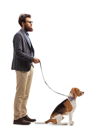 Full length profile shot of a bearded man standing with a beagle dog on a leash isolated on white backgroundの写真素材