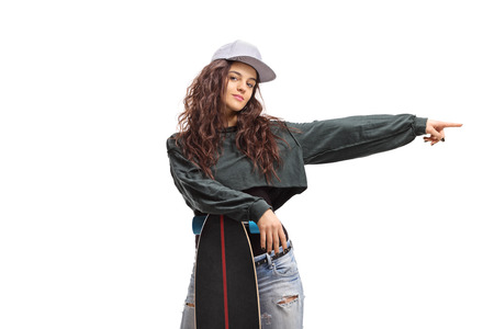 Skater girl posing with a longboard and pointing isolated on white background