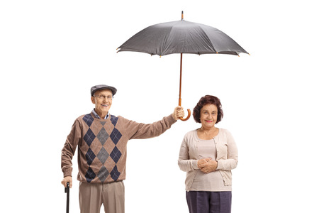 Elderly gentleman holding an umbrella over an elderly lady isolated on white backgroundの写真素材