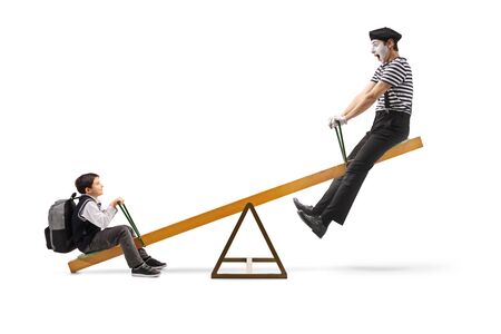 Full length profile shot of a schoolboy and a mime on a seesaw isolated on white backgroundの写真素材