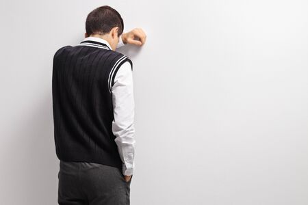 Upset teenage student with his head against a wallの販売画像
