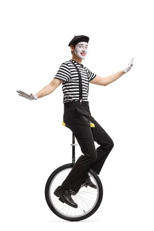 Full length profile shot of a mime riding a unicycle and making a grimace isolated on whiteの写真素材