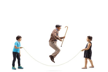 Full length profile shot of a boy and girl holding a rope and a senior man with a cane jumping isolated on whiteの写真素材