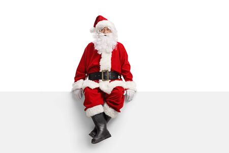 Full length portrait of a santa claus sitting on a white banner isolated on white backgroundの写真素材