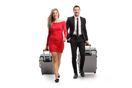 Full length portrait of a young woman and man with suitcases walking towards the camera isolated on white backgroundの写真素材