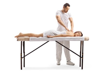 Professional masseur giving massaging a woman on a bed isolated on whiteの写真素材