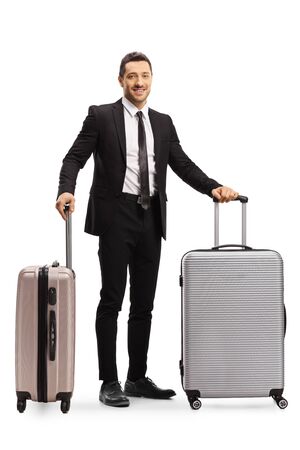 Full length portrait of a man in a suit posing with two suitcases isolated on white backgroundの写真素材