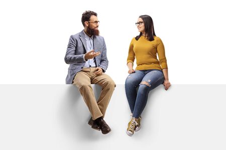 Full length shot of a bearded man talking to a young female seated on a banner isolated on white backgroundの写真素材