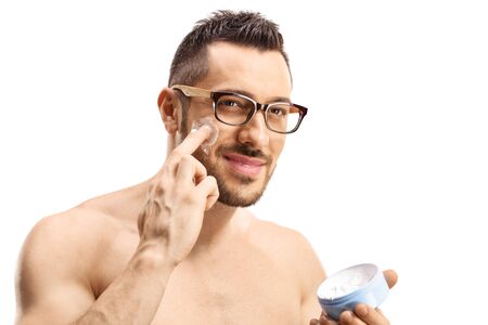 Portrait of a handsome man applying face cream isolated on whiteの写真素材