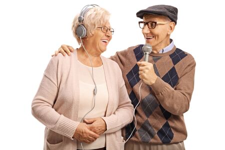 Elderly man singing on a microphone to an elderly woman with headphones isolated on white background