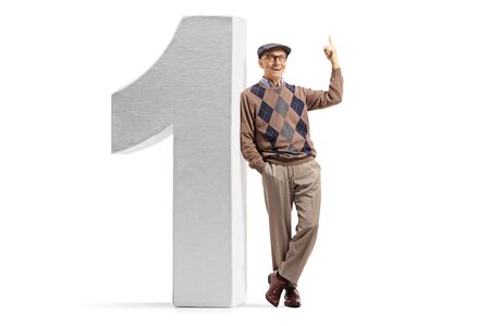 Full length portrait of a cheerful senior pointing up and leaning on a big number one isolated on whiteの写真素材