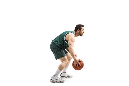 Full length profile shot of a basketball player in a green jersey with a ball isolated on white backgroundの写真素材