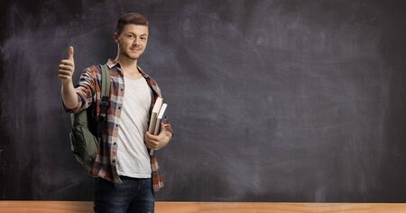 Male student with a school blackboard showing a thumb up gesture