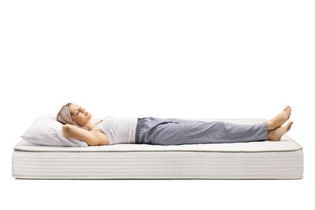 Young woman sleeping on a bed mattress isolated on white backgroundの写真素材