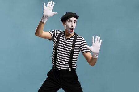 Pantomime man touching an imaginary glass isolated on blue backgroundの写真素材