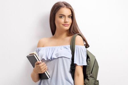 Female student with backpack and books smiling at the cameraの写真素材