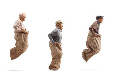Senior people playing gunny race and jumping in a sack isolated on white backgroundの写真素材