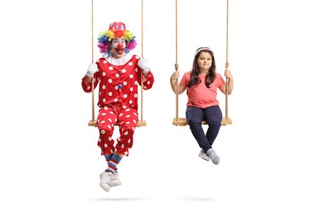 Happy clown and a girl sitting on wooden swings isolated on white backgroundの写真素材