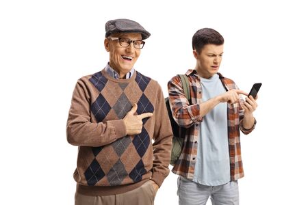 Senior man laughing and pointing at a young guy using a mobile phone isolated on white background