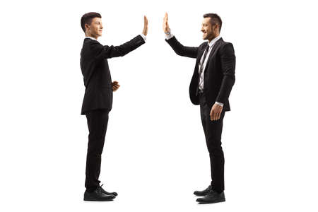 Full length shot of men in suits gesturing high-five isolated on white background