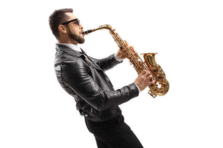 Profile shot of a musician in a leather jacket wearing sunglasses and playing a saxophone isolated on white backgroundの写真素材