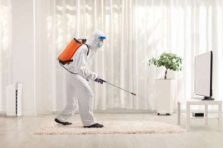 Man in a hazmat suit sanitising a room in an apartmemtの写真素材
