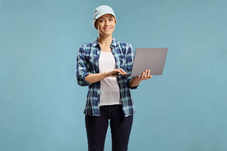Casual young woman holding a laptop on a blue background