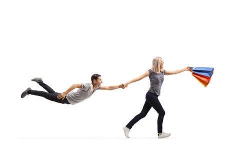 Woman shopaholic running and pulling her boyfriend isolated on white background
