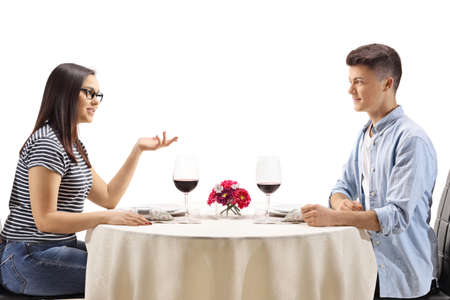 Teenagers sitting at a restaurant table and talking isolated on white backgroundの写真素材