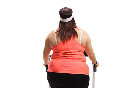 Rar view of an overweight woman on a treadmill isolated on white backgroundの写真素材