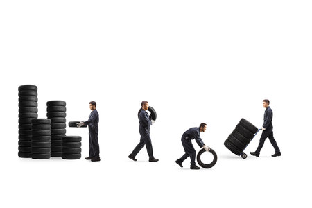 Auto mechanic workers carrying car tires isolated on white backgroundの写真素材