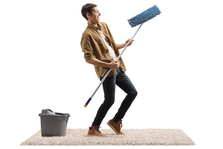 Happy man dancing and making air guitar with a cleaning mop isolated on white backgroundの写真素材