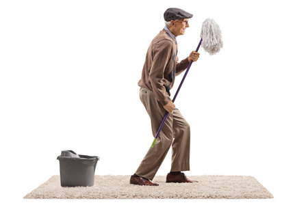 Profile shot of an elderly man dancing with a cleaning mop isolated on white backgroundの写真素材
