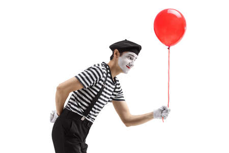 Profile shot of a mime giving a red balloon isolated on white backgroundの写真素材