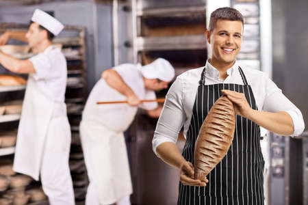 Male workers in a bakery baking breadの写真素材