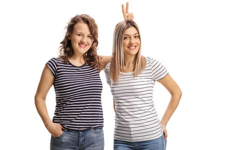 Female friends posing and making bunny ears on head isolated on white background