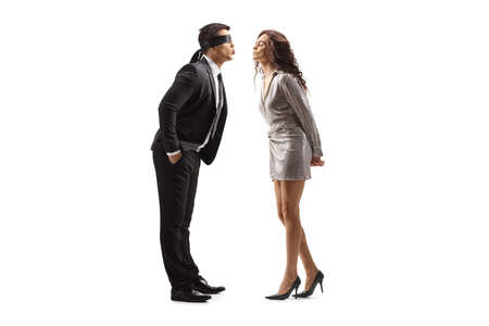 Full length profile shot of a man in a suit with blindfold kissing a woman in a dress isolated on...