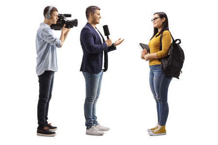 Full length profile shot of a reporter interviewing a female student and cameraman recording isolated on white backgroundの写真素材