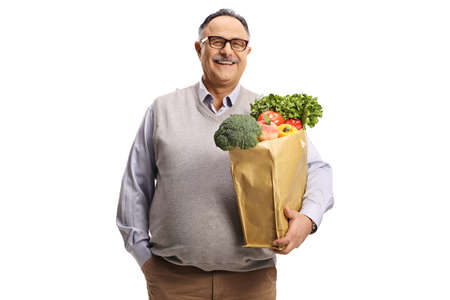 Smiling mature man holding a grocery bag with healthy food isolated on white backgroundの写真素材