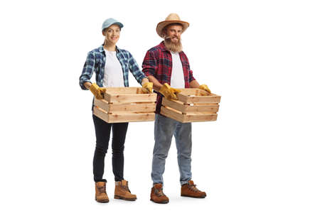 Full length portrait of a male and female farmers carrying crates isolated on white backgroundの写真素材