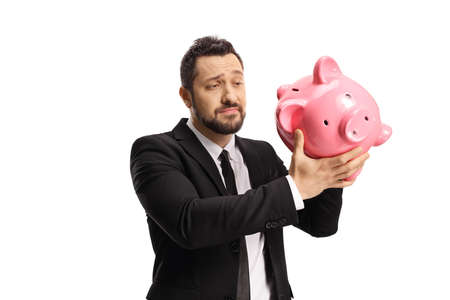 Sad businessman looking at an empty piggybank isolated on white backgroundの写真素材