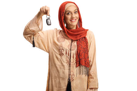 Excited muslim woman showing a car key and smiling isolated on white background